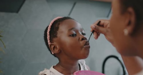 Child Being Fed Food by an Adult Indoors