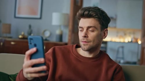 Man On Couch Video Calling With Smartphone