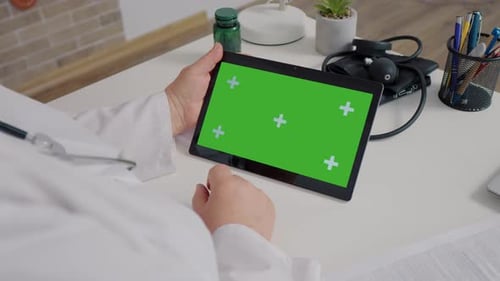Unrecognized female doctor watching chroma key horizontal tablet.