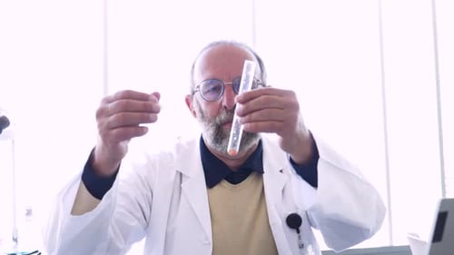 Senior scientist inspecting a test tube with pipette in science laboratory