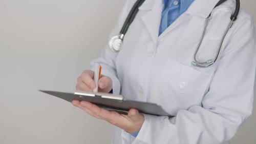 Doctor in Lab Coat Writing on Clipboard