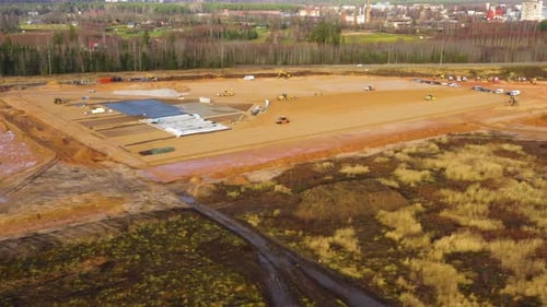 Vista aérea de un extenso sitio de construcción con avances en el movimiento de tierras