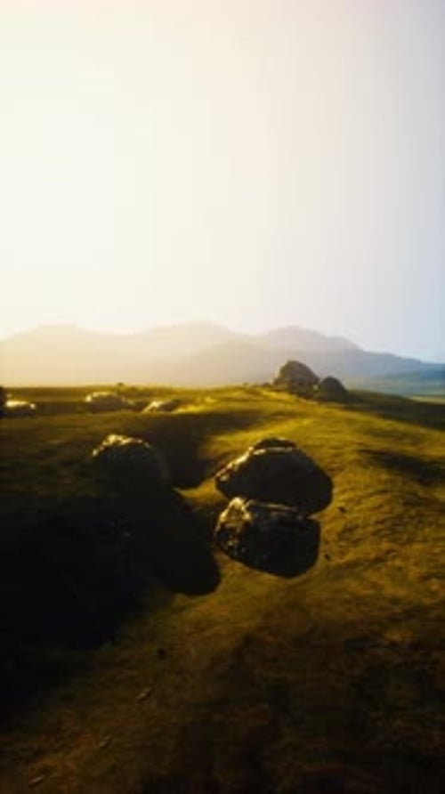 Grassy Field With Rocks and Mountains