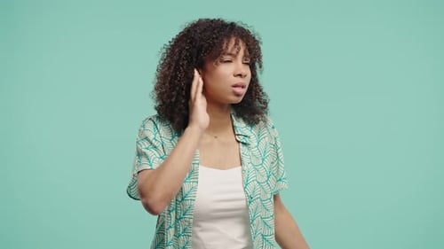 African Girl Pointing To Ear With Confused FaceSignaling She Cant Hear Clearly