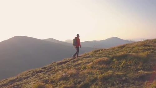 Tourist Hiker with a Backpack in Orange Jacket Walking on Mountain Path in Carpathian Mountains
