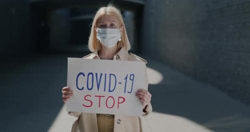 Woman Holding COVID-19 Stop Sign Outdoors