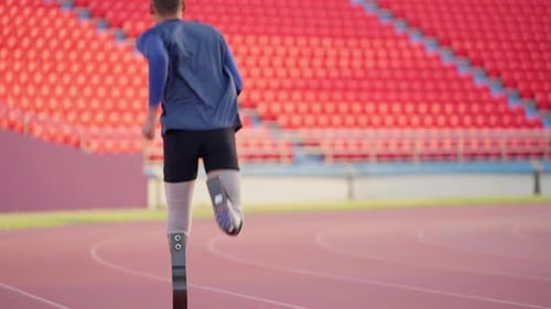 Slow motion shot back and close up of sport man athlete prosthesis legs is jogging on track