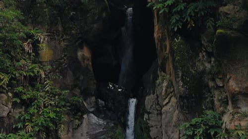 Scenic Waterfall Cascading Down Rocky Cliff Surrounded By Lush Greenery
