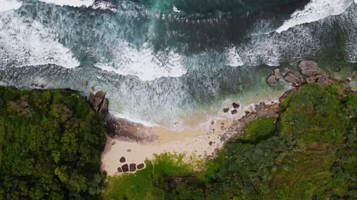 Overhead drone shot of uninhabited White sandy beach between cliffs - Tropical beach of Indonesia