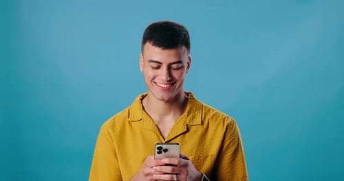 Happy man, smartphone and laughing for funny joke, social media or meme on blue studio background