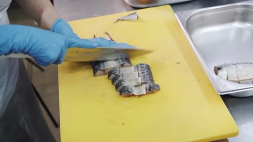 Gloved Hands Expertly Cutting Fish on Yellow Board
