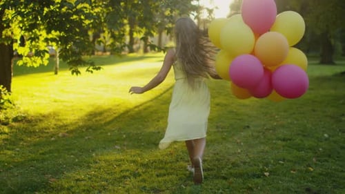 Girl is Running at Park with Balloons in Hand at Sunset Time