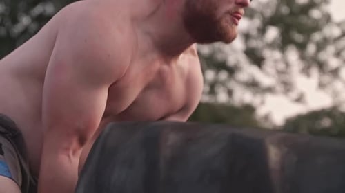 Mann dreht Reifen beim Training von der Seite um, Nahaufnahme, Zeitlupe