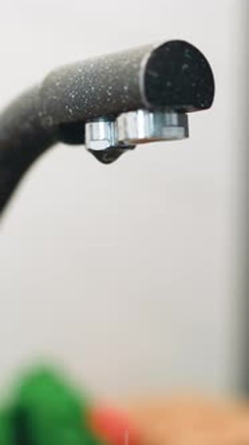 Drops of Water Drip From Dark Modern Faucet Into Sink