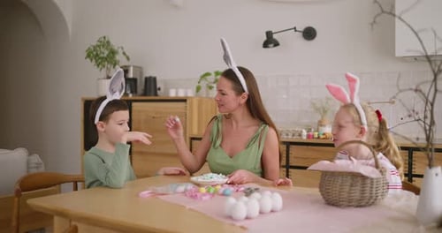 Mom Sits at the Table with Her Children and Eats Sweets During the Easter Holiday at Home