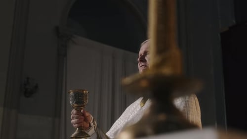 Oberpriester hält Kelchbecher in der Hand und spricht während der Kommunionzeremonie