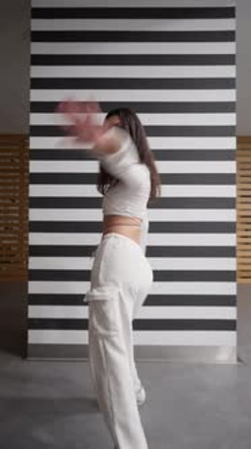 Young Woman Dancing in Front of Striped Wall