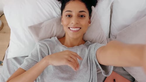 Smiling Woman Waving in Bed on Video Call