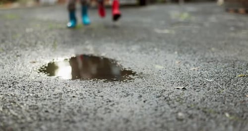 Children, feet and jumping in water puddle on winter holiday travel, happiness and joy together