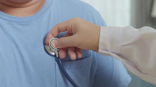 Close Up Of A Male Doctor's Hand Using Stethoscope With A Patient For Medical Check Up In Clinic