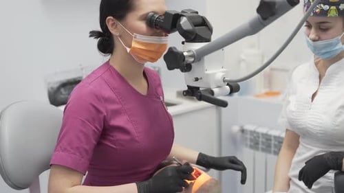 Female Dentist Performing Dental Procedure with Microscope