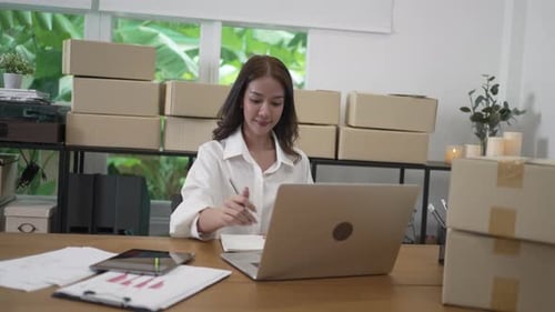 Young female entrepreneur is packing merchandise at home.