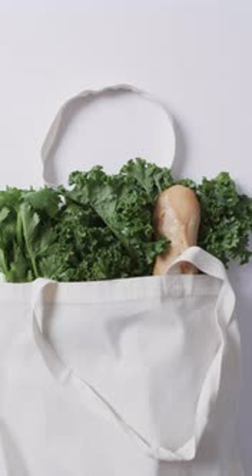 Vídeo vertical de bolsa de lona negra con perejil, col rizada y baguette, espacio para copiar sobre fondo blanco