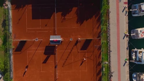 Aerial Video Aerial Shot of Tennis Courts By a Marina With White Yachts and Azure Water
