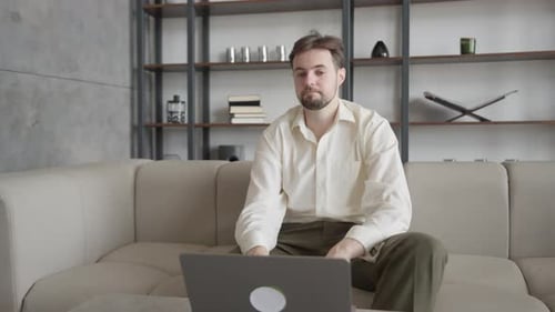 Man Reacting In Disbelief Looking At Laptop Screen While Sitting On Modern Sofa