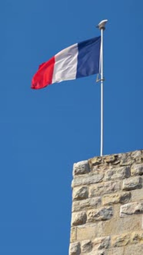 The flag of France waving with the blue sky on the background. Vertical