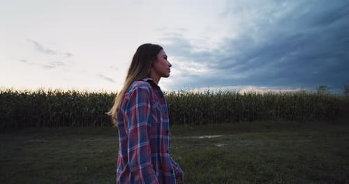 Happy Woman Smiling and Looking Around While Walking in a Green Field of Corn.