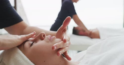 Nahaufnahme zweier junger Freundinnen mit einem Handtuch auf dem Kopf, die eine Gesichtsmassage und einen Wellness-Aufenthalt erhalten