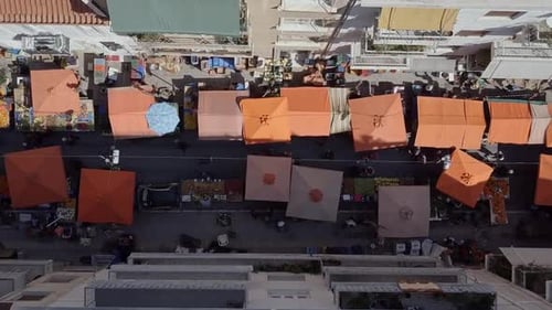 Aerial drone shot looking down street with busy street market Athens Greece