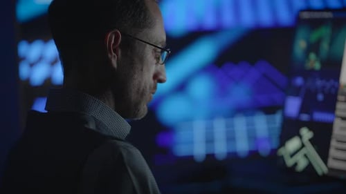 Man Coding at Computer in Blue Lit Office