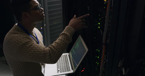 4k video footage of a young IT technician standing alone in a server ...