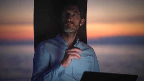 Ein konzentrierter Profi, der fleißig bei Sonnenuntergang an den ruhigen Meereswellen in der Nähe arbeitet