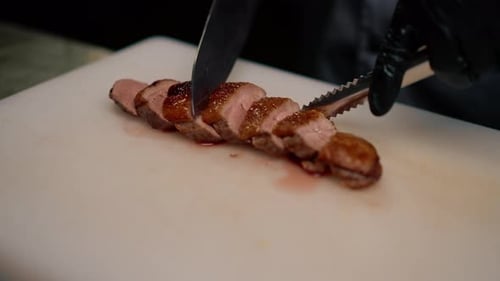 Professional restaurant kitchen chef cuts delicious roasted duck breast with a knife asian cuisine