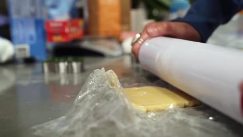 A rolling pin flattening a circle of sugar cookie dough from the side in order to bake Holiday Chris