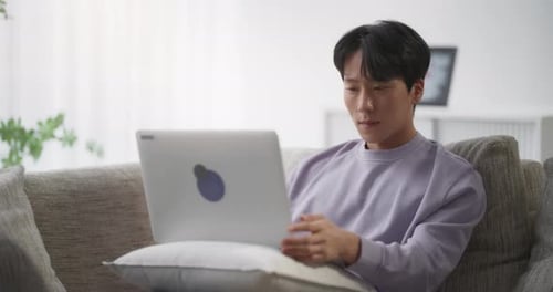 Man Using Laptop on Sofa Indoors