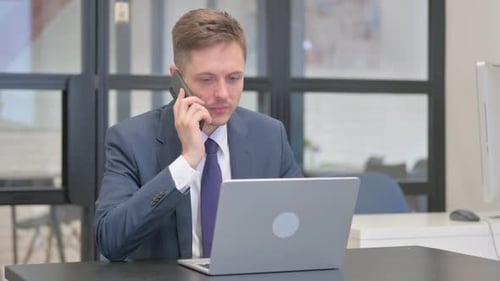Adult Man in Suit Talking on Phone at Desk
