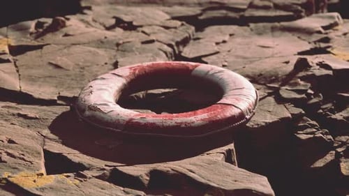 Weathered Lifebuoy Resting on Textured Rocks