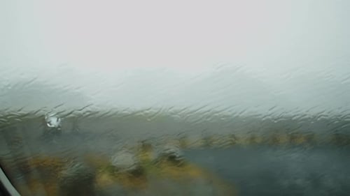 Heavy rain falling on a car window. The car is parked on a parking lot in the Icelandic wilderness