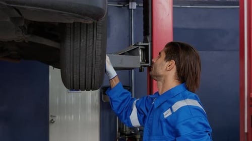 Young man is mechanic repair tires wheel car in the garage with professional, auto service.