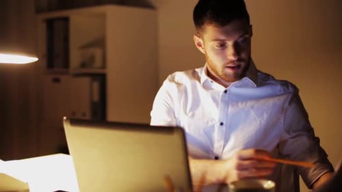Man working late at night in modern office overwhelmed by business deadline