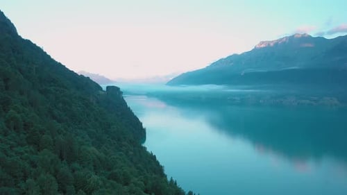 Drone flight over a beautiful Swiss alpine lake. The drone flies above the valley forest to reveal t