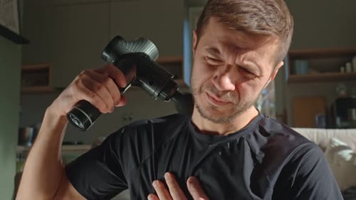 Man Using Massage Gun on Neck Muscles