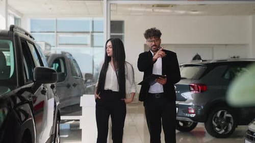 Salesman Discussing Car Features With a Woman in Showroom