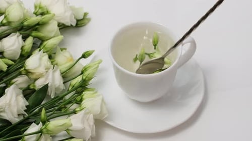 Herbal Tea Stirred by Spoon near White Flowers