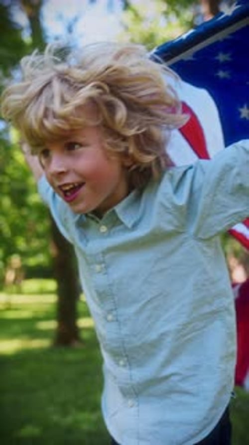 Child Runs Waving American Flag Through a Green Park