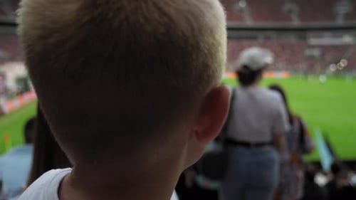A View From the Back of a Boy During a Football Match in a Crowded Stadium